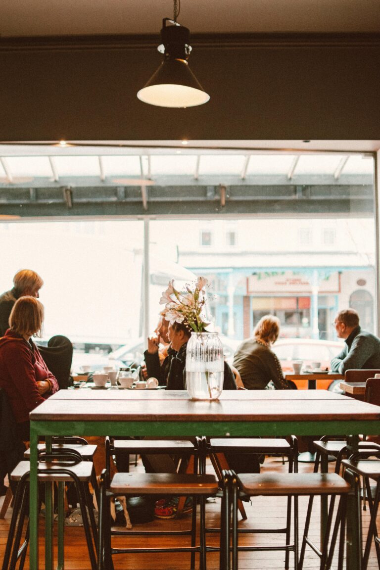 A warm and inviting café interior with people relaxing and drinking coffee by the window.